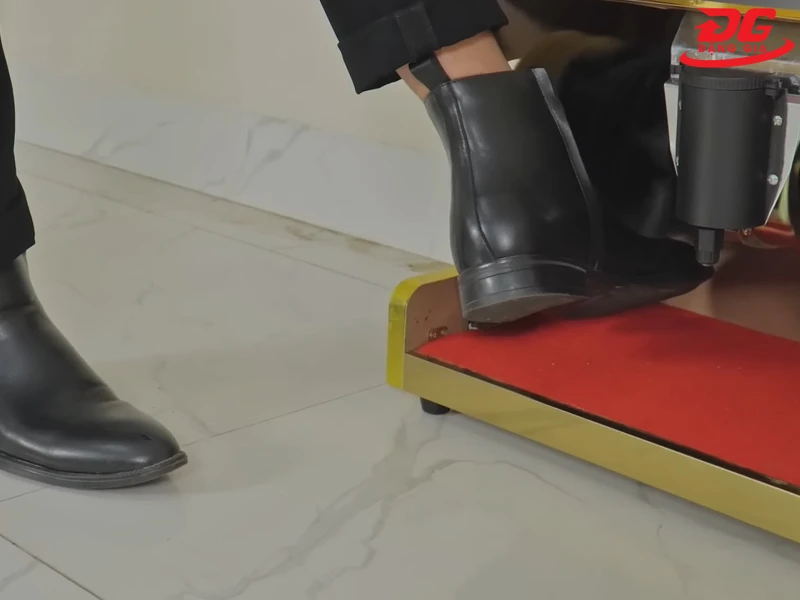 Đưa giày vào vị trí bàn chải đánh bụi để làm sạch bụi bẩn